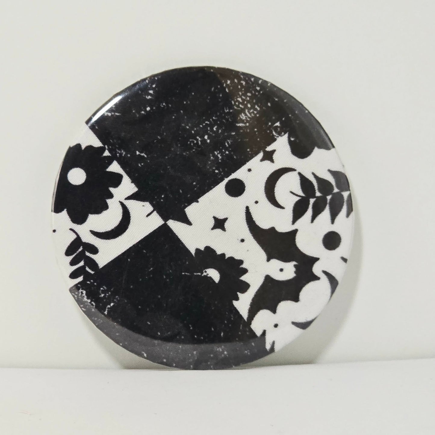 Round black and white decorative item with geometric patterns on a light gray background