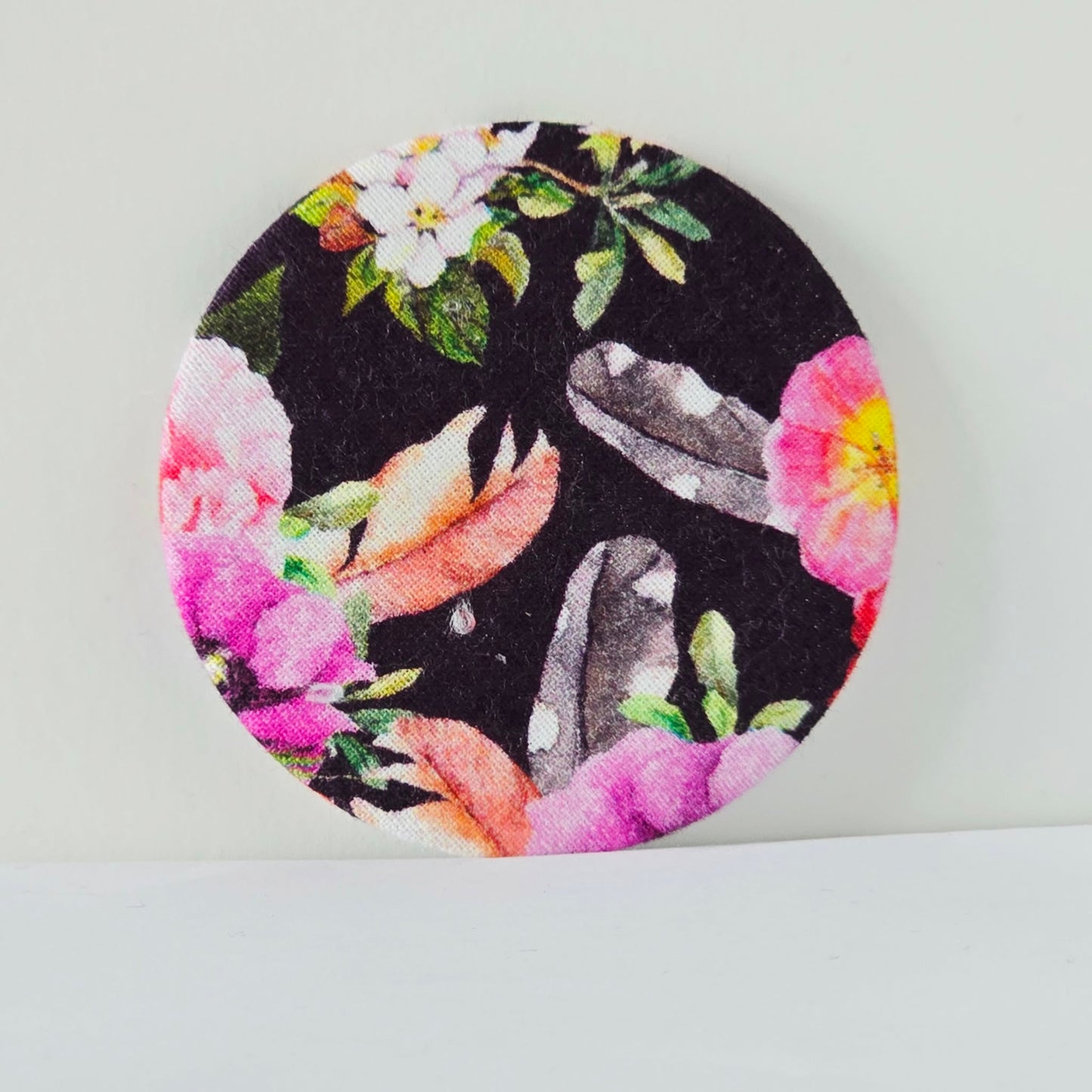Round fabric patch with floral and bird design on a black background