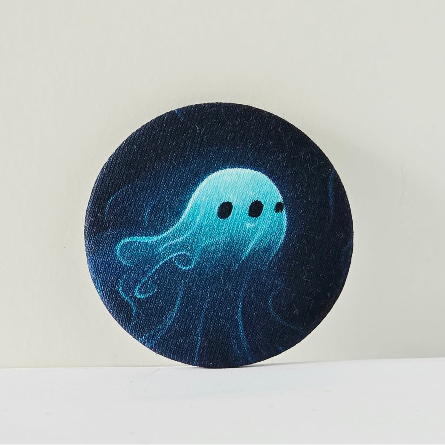 Circular dark blue fabric patch with a light blue jellyfish design on a white background