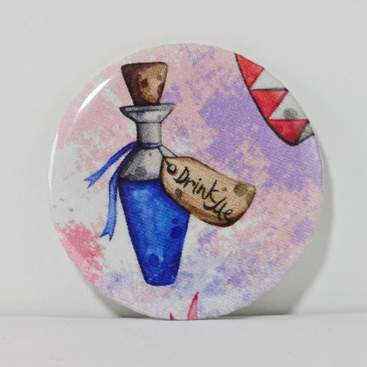 Round button badge with a blue potion bottle and 'Drink Me' label on a colorful background
