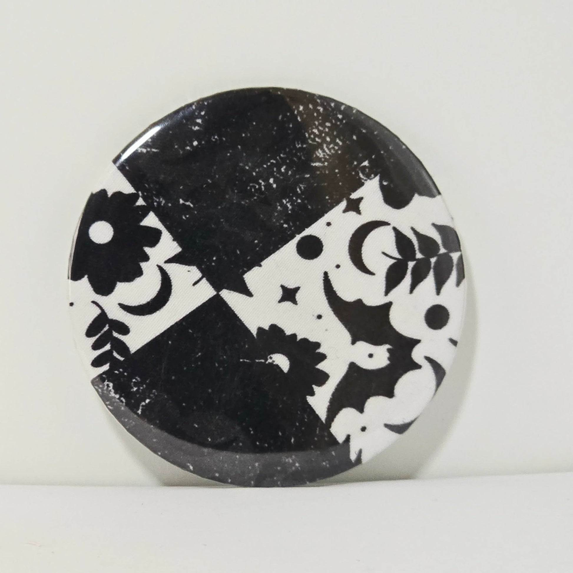 Round black and white decorative item with geometric patterns on a light gray background