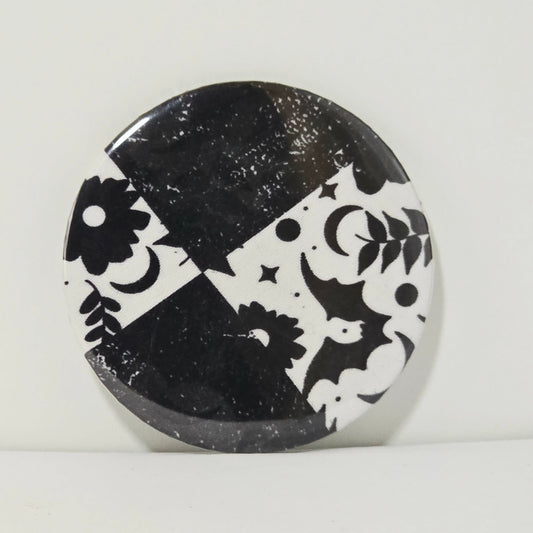 Round black and white decorative item with geometric patterns on a light gray background