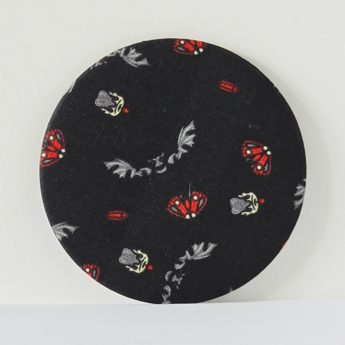 Round black fabric patch with butterfly pattern on a white background
