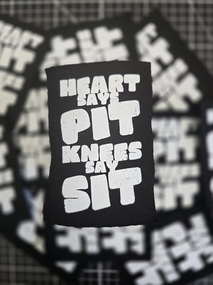 Black patch with white text 'Heart Over Knives' on a blurred background of similar patches.