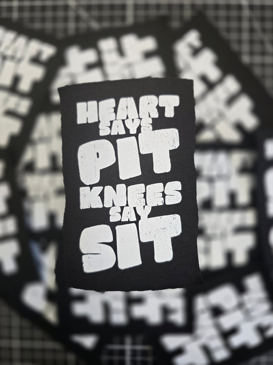 Black patch with white text 'Heart Over Knives' on a blurred background of similar patches.