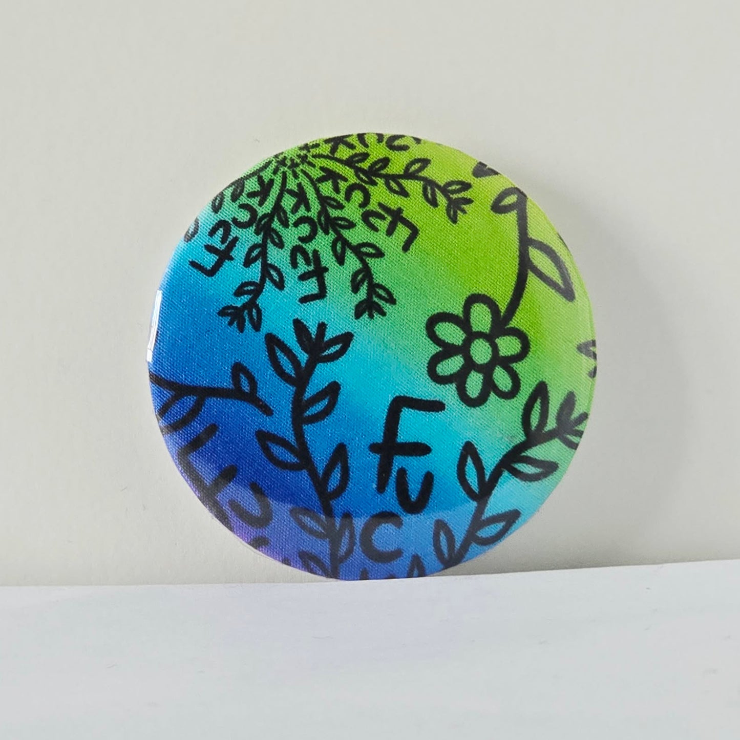 Round decorative item with floral patterns on a gradient blue and green background