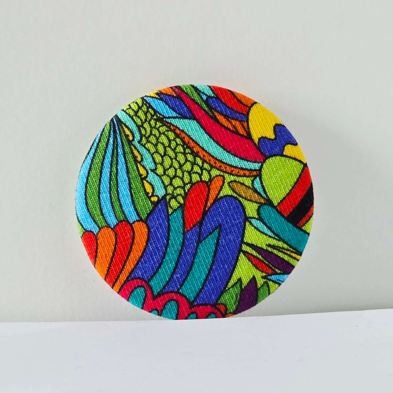 Colorful circular fabric patch with abstract design on a white background