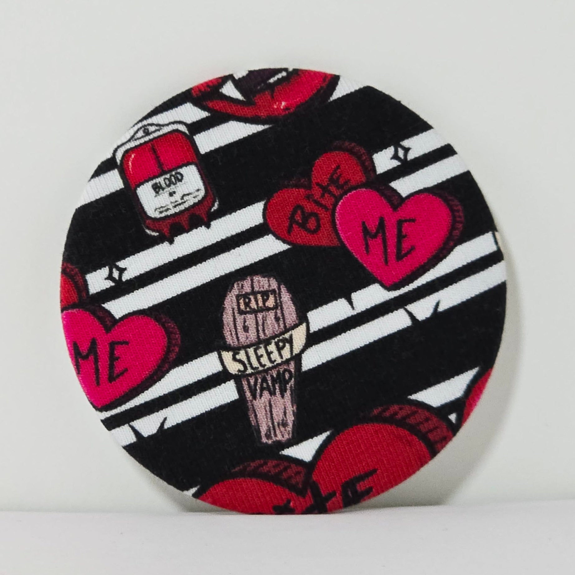 Round product with black and white striped pattern, red hearts, and text on a white background