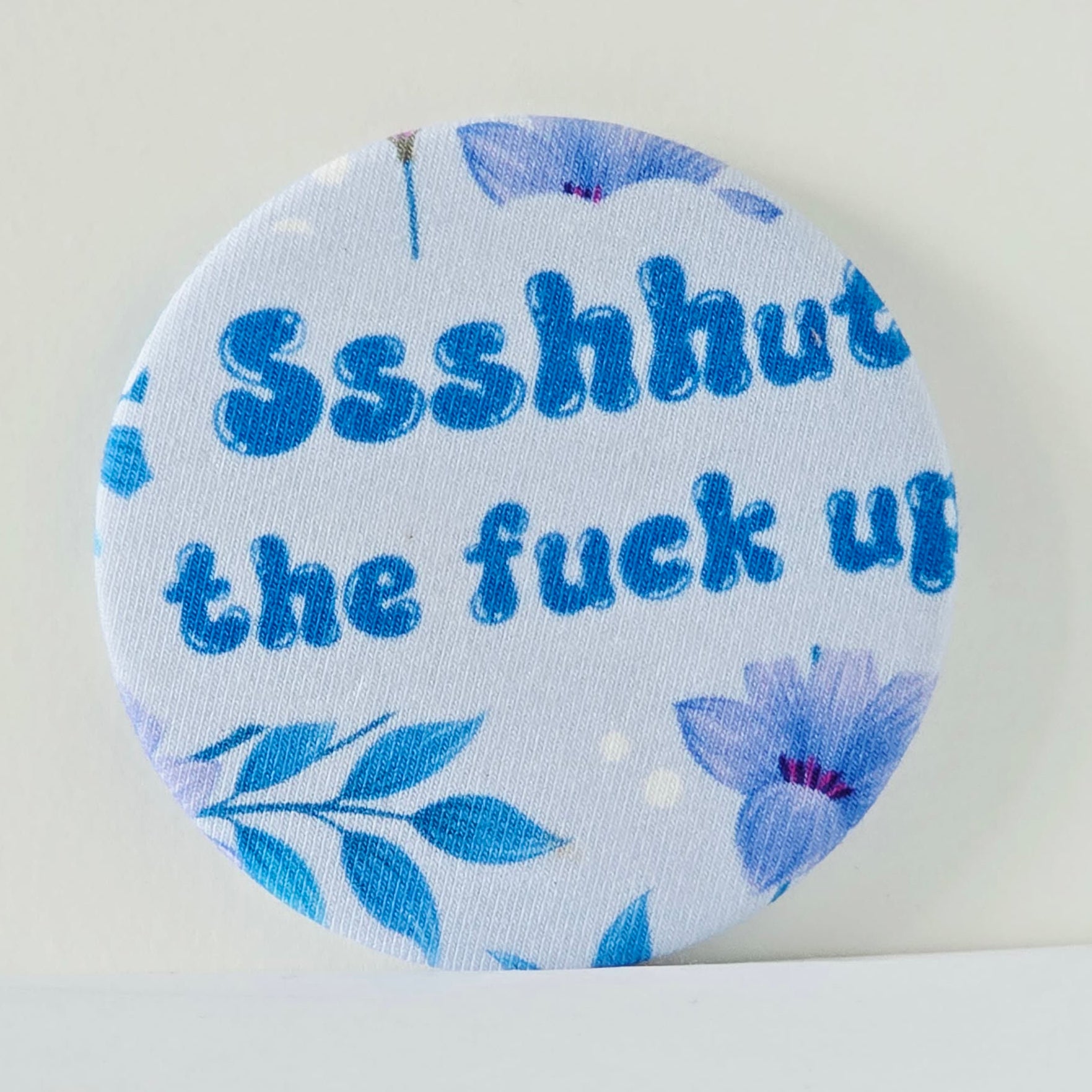 Round magnet with blue floral design and text on a white background
