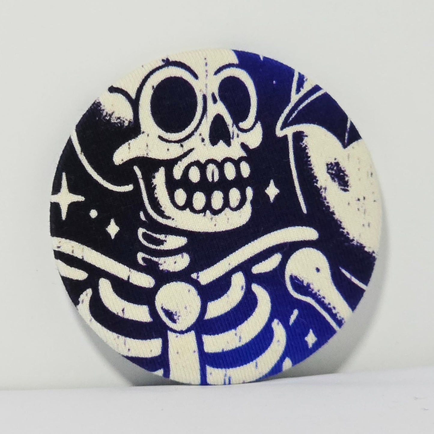 Round ceramic magnet with a blue and white skeleton design on a blue background