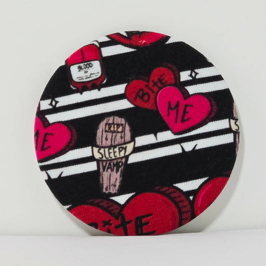 Round product with black and white striped pattern, red hearts, and text on a white background