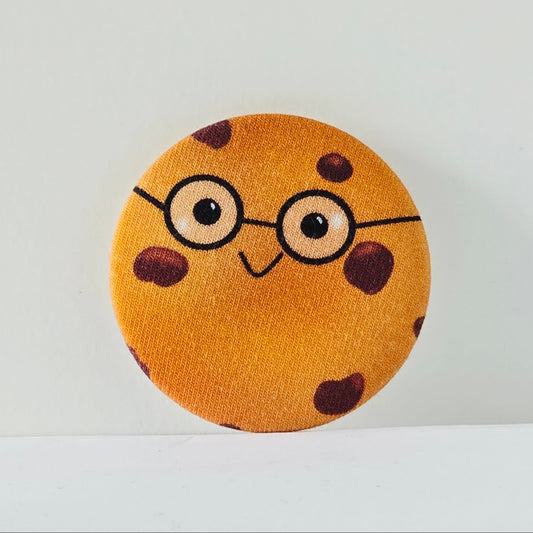 Round fabric badge with a cookie design wearing glasses on a white background