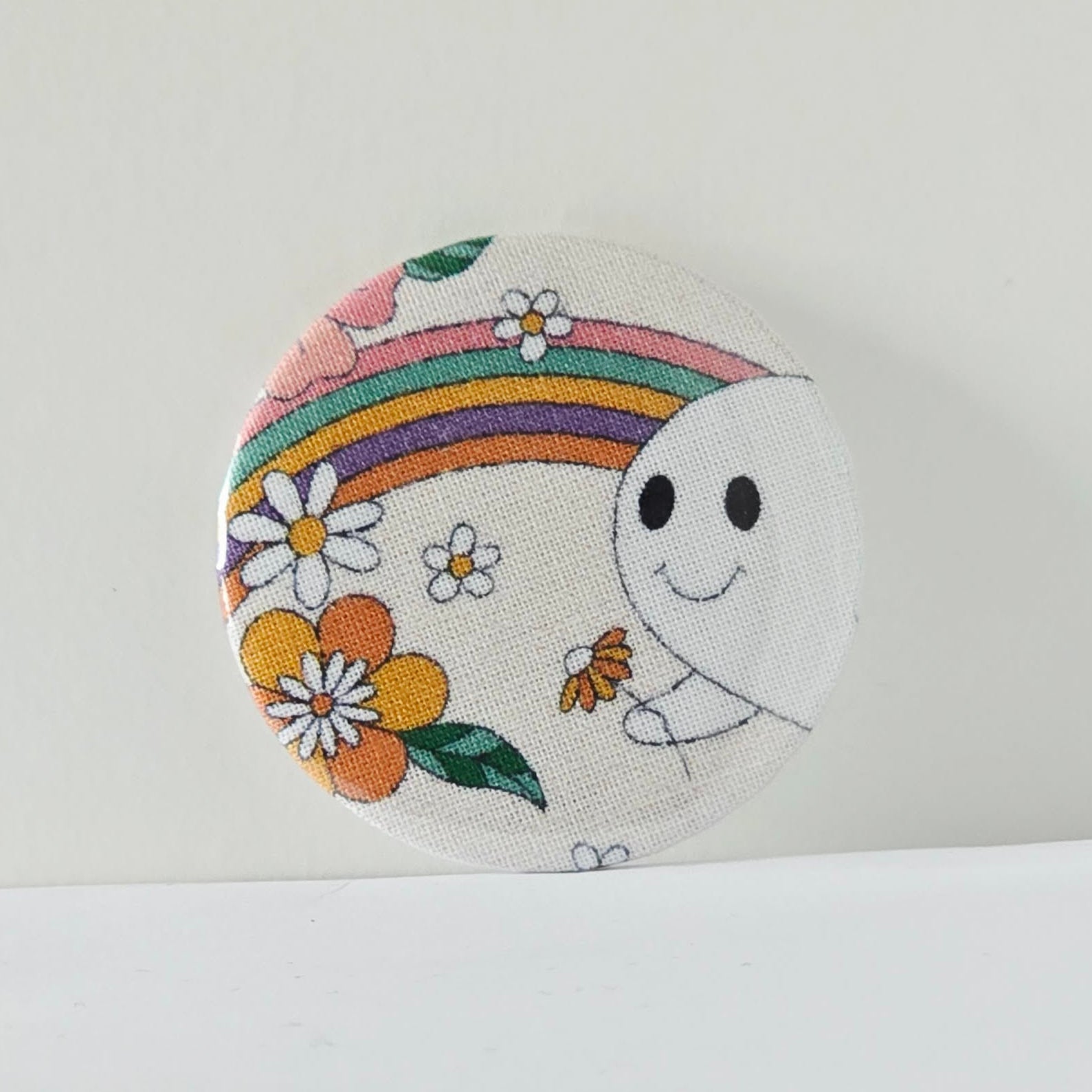 Circular pouch with cartoon ghost and rainbow design on a white background
