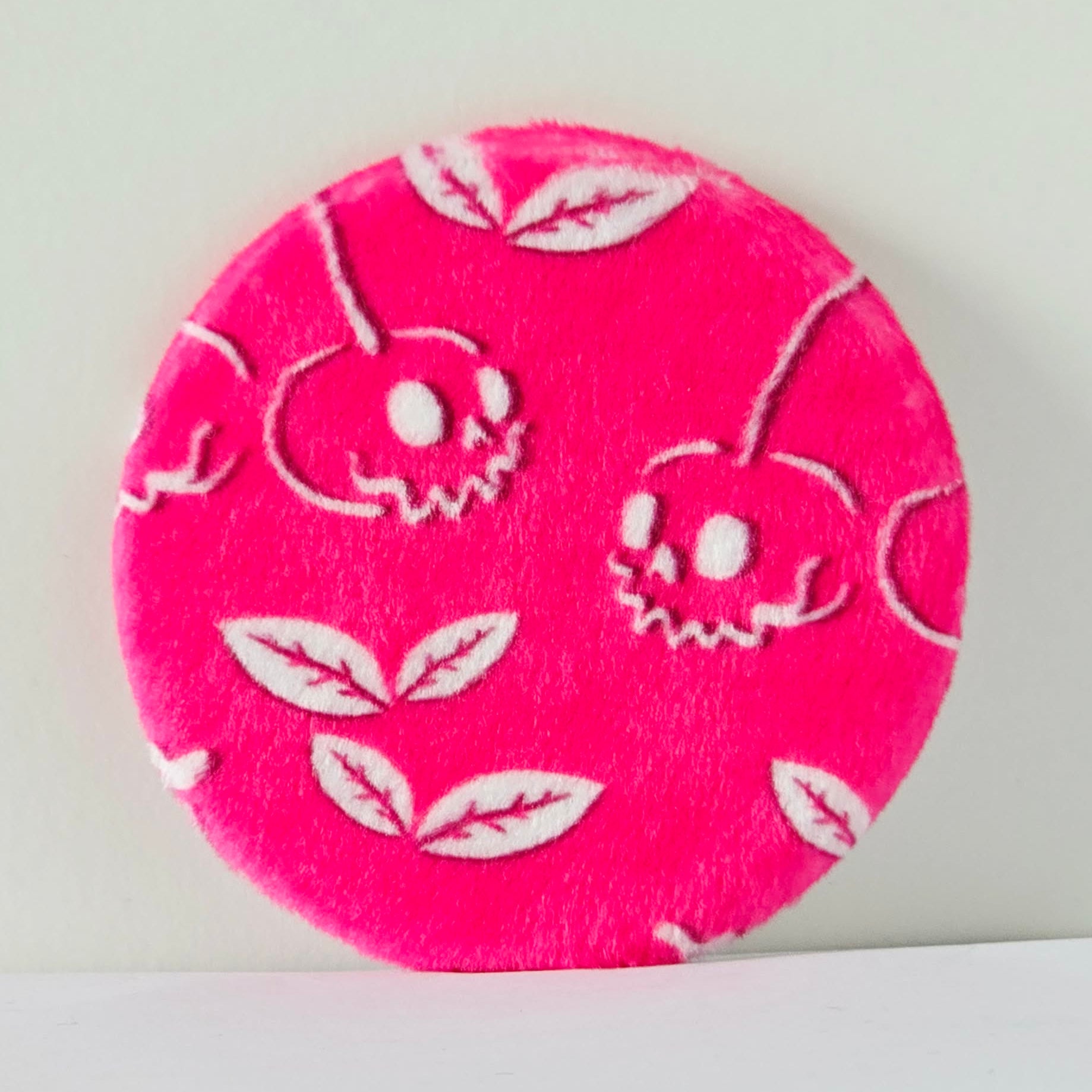Pink circular fabric patch with white floral patterns on a light gray background