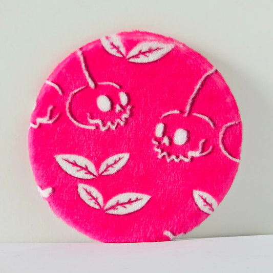 Pink circular fabric patch with white floral patterns on a light gray background