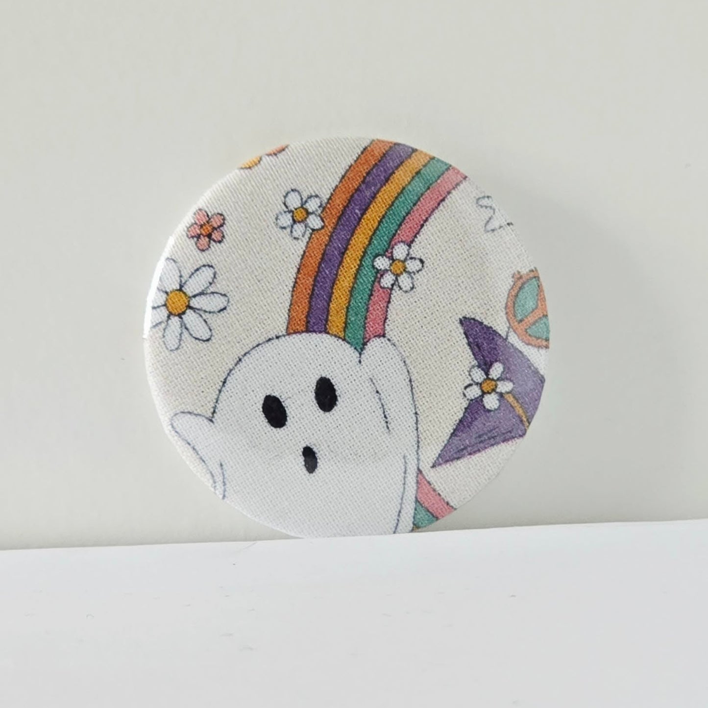 Circular patch with a ghost, rainbow, and flowers on a white background