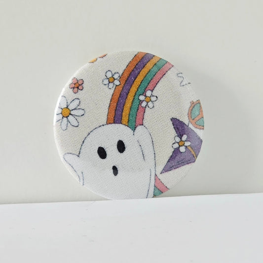 Circular patch with a ghost, rainbow, and flowers on a white background