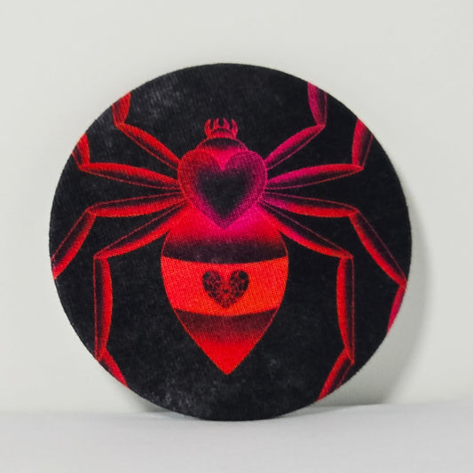 Circular coaster with red spider design on a black background