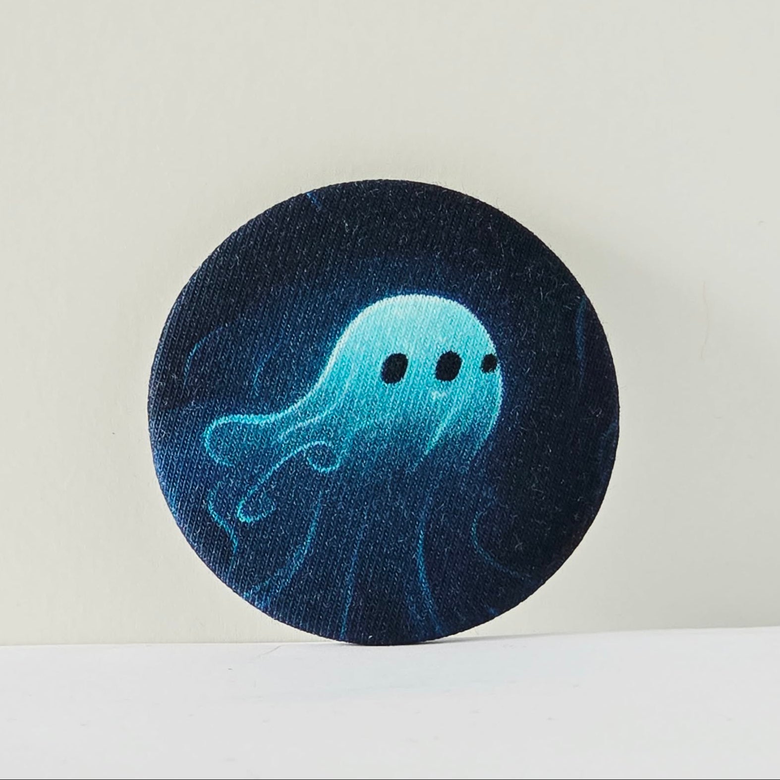 Circular dark blue fabric patch with a light blue jellyfish design on a white background